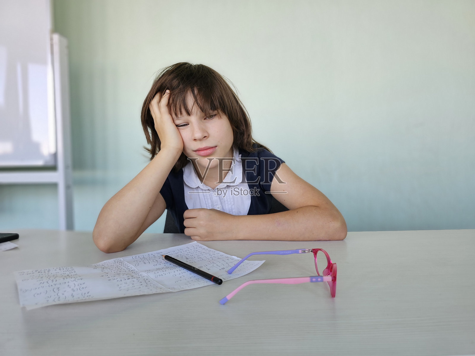 放学后,女孩躺在教室的课桌上休息,准备回到学校。照片摄影图片
