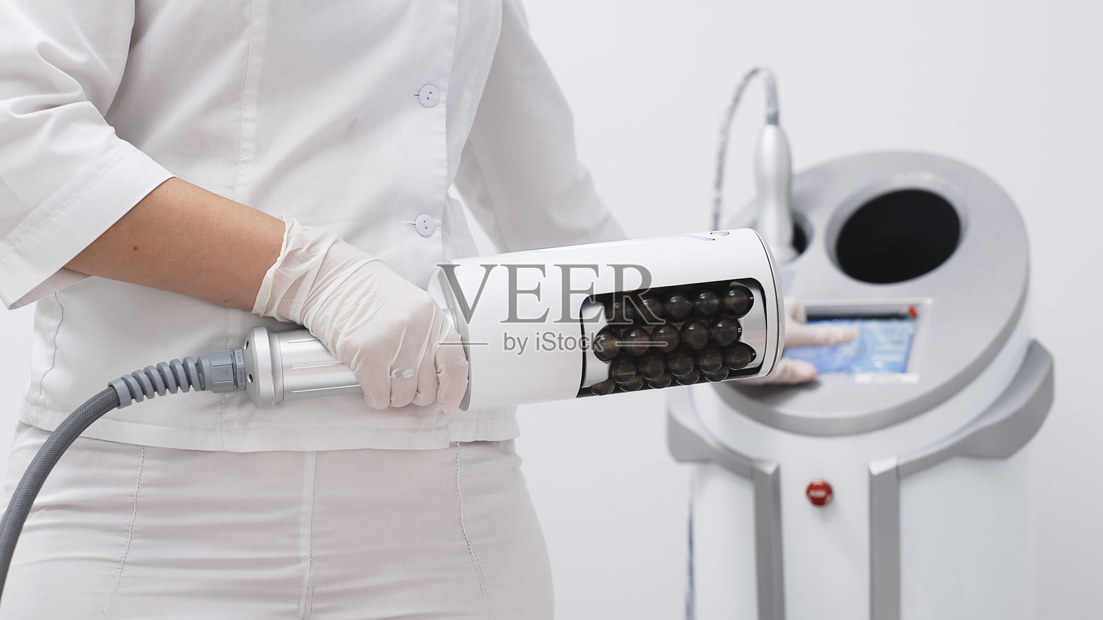 在现代诊所使用微振疗法设备进行深层脂肪团减少和身体塑形的专业人士照片摄影图片