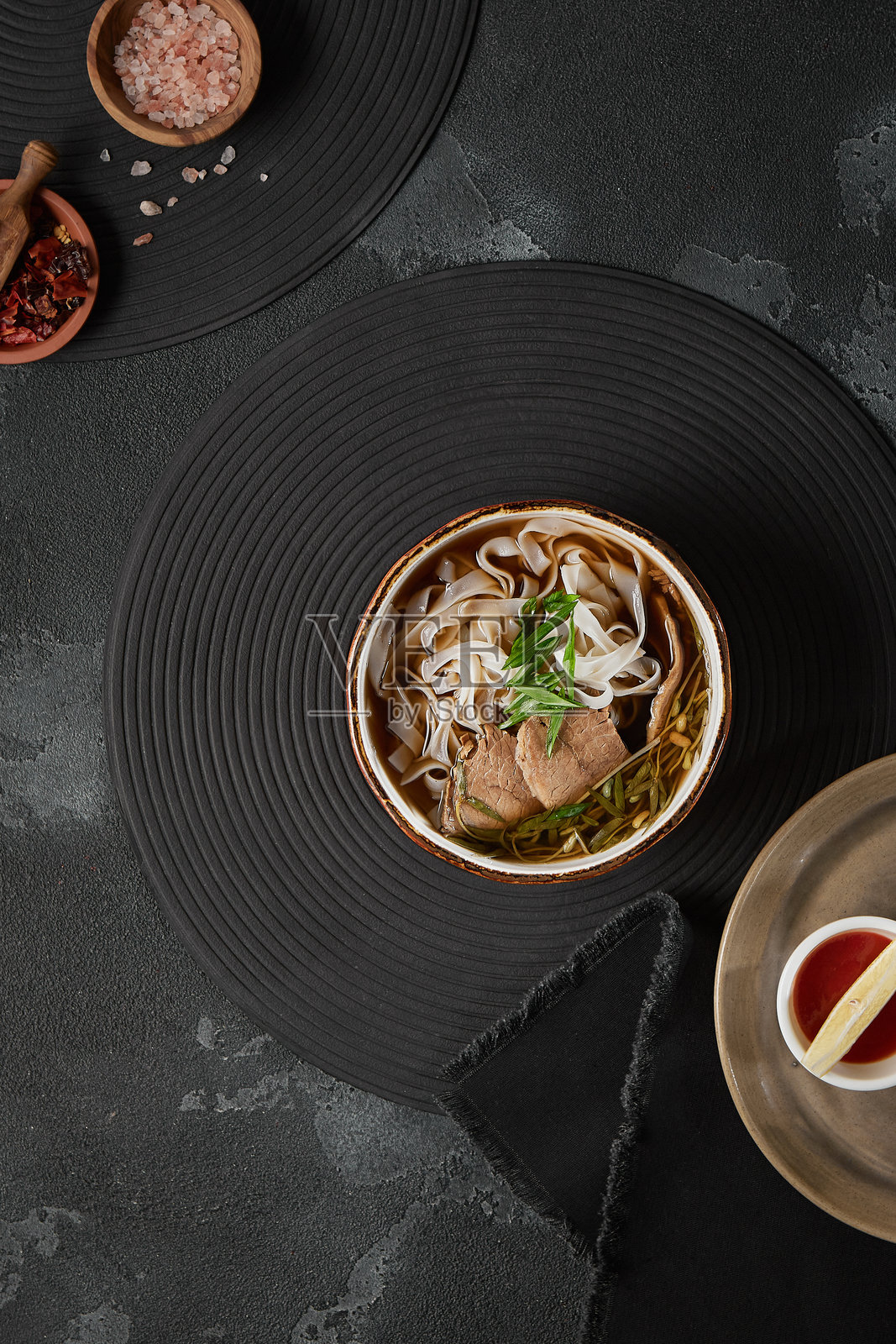 越南牛肉河粉的鸟瞰图,展现了新鲜食材和深色现代美学的正宗牛肉汤照片摄影图片