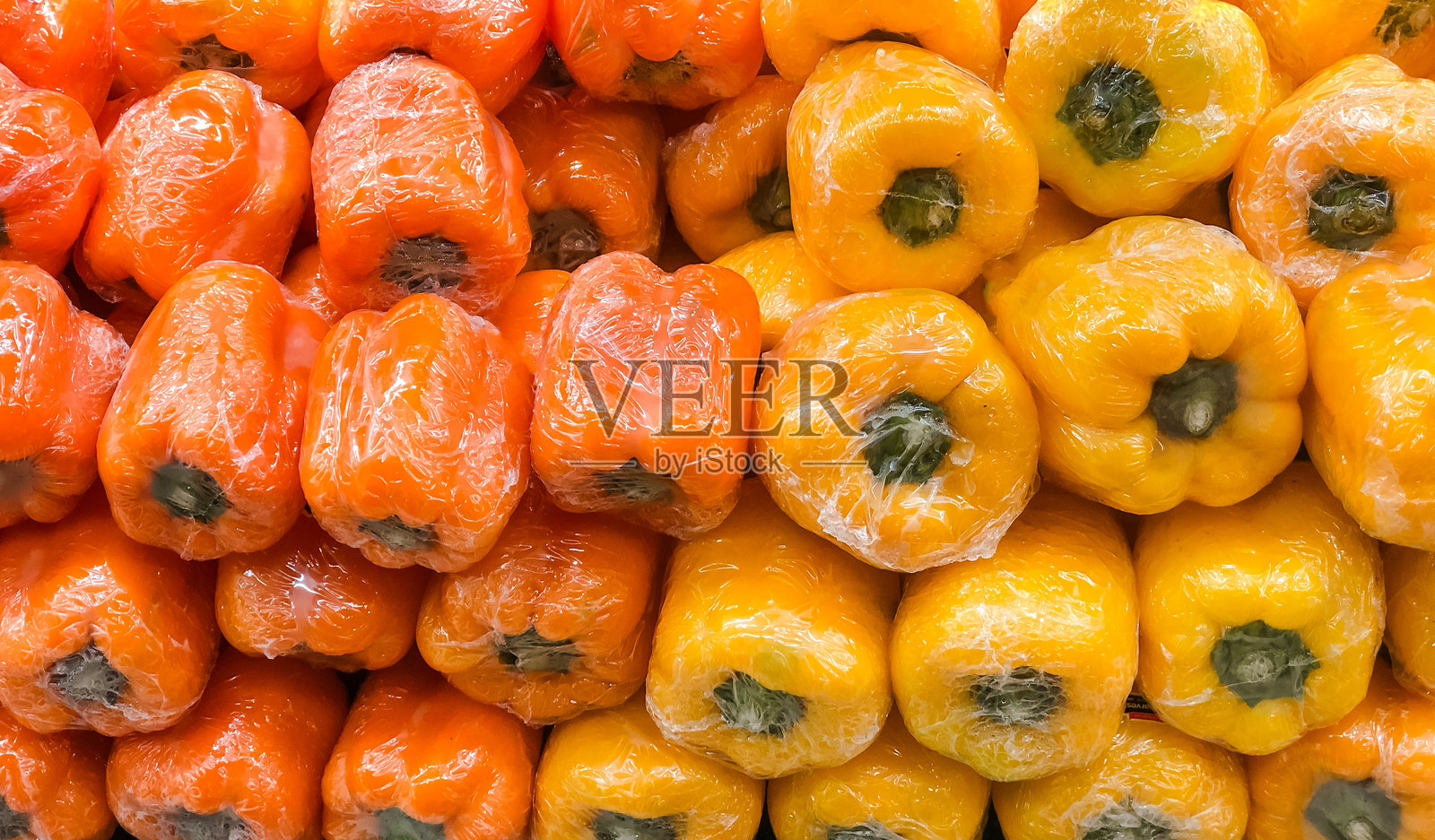 新鲜的黄色和绿色甜椒用塑料包装。照片摄影图片