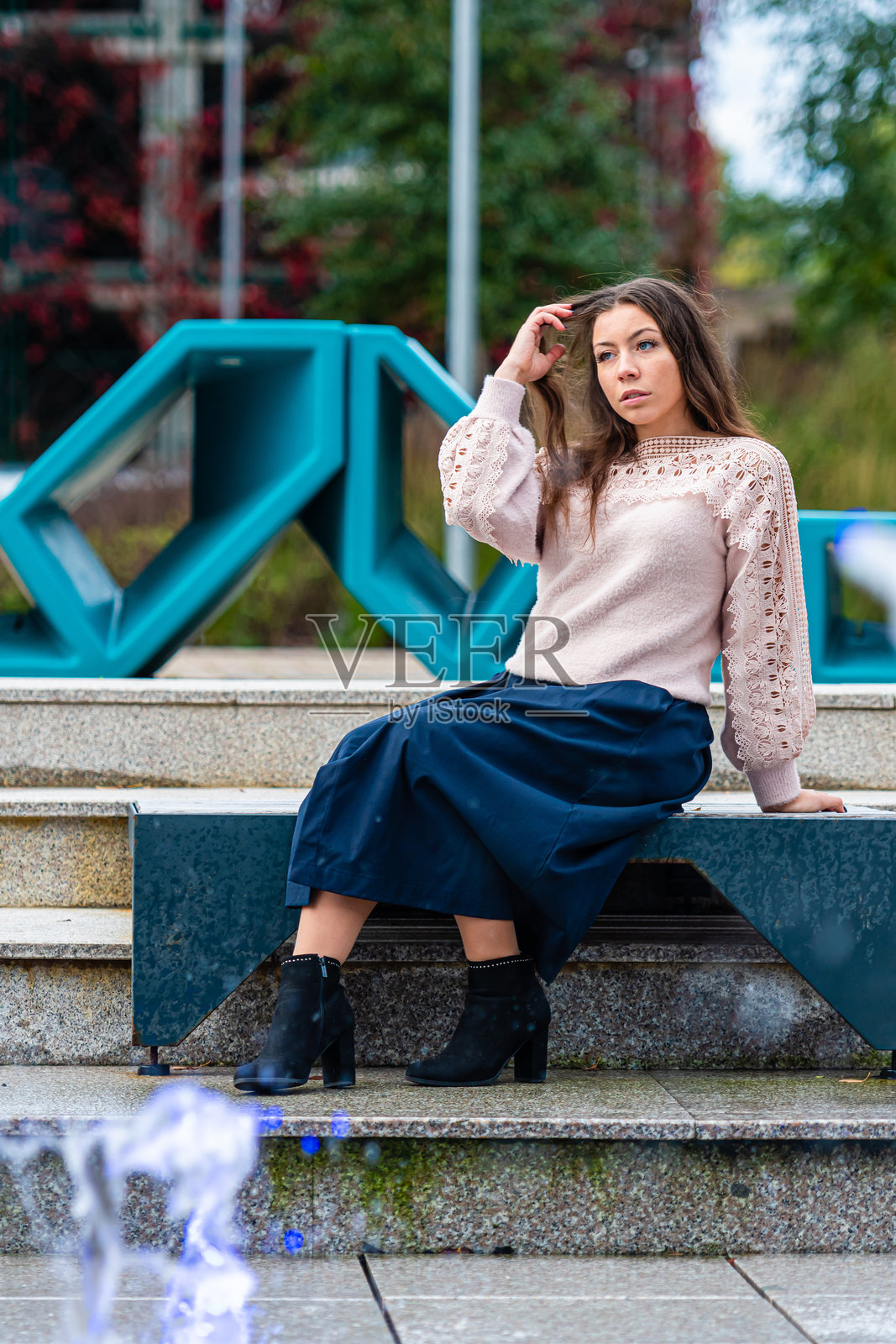 年轻女性在城市环境中的现代艺术装置旁优雅地摆姿势。照片摄影图片