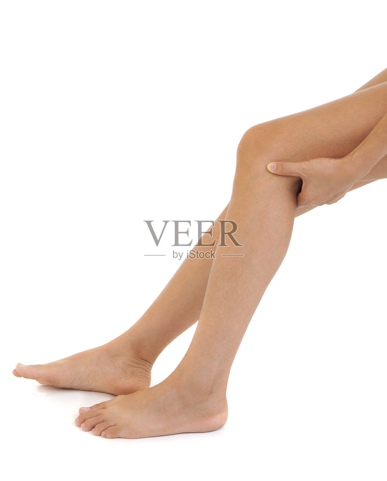 女性低头触摸膝盖,背景为白色照片摄影图片