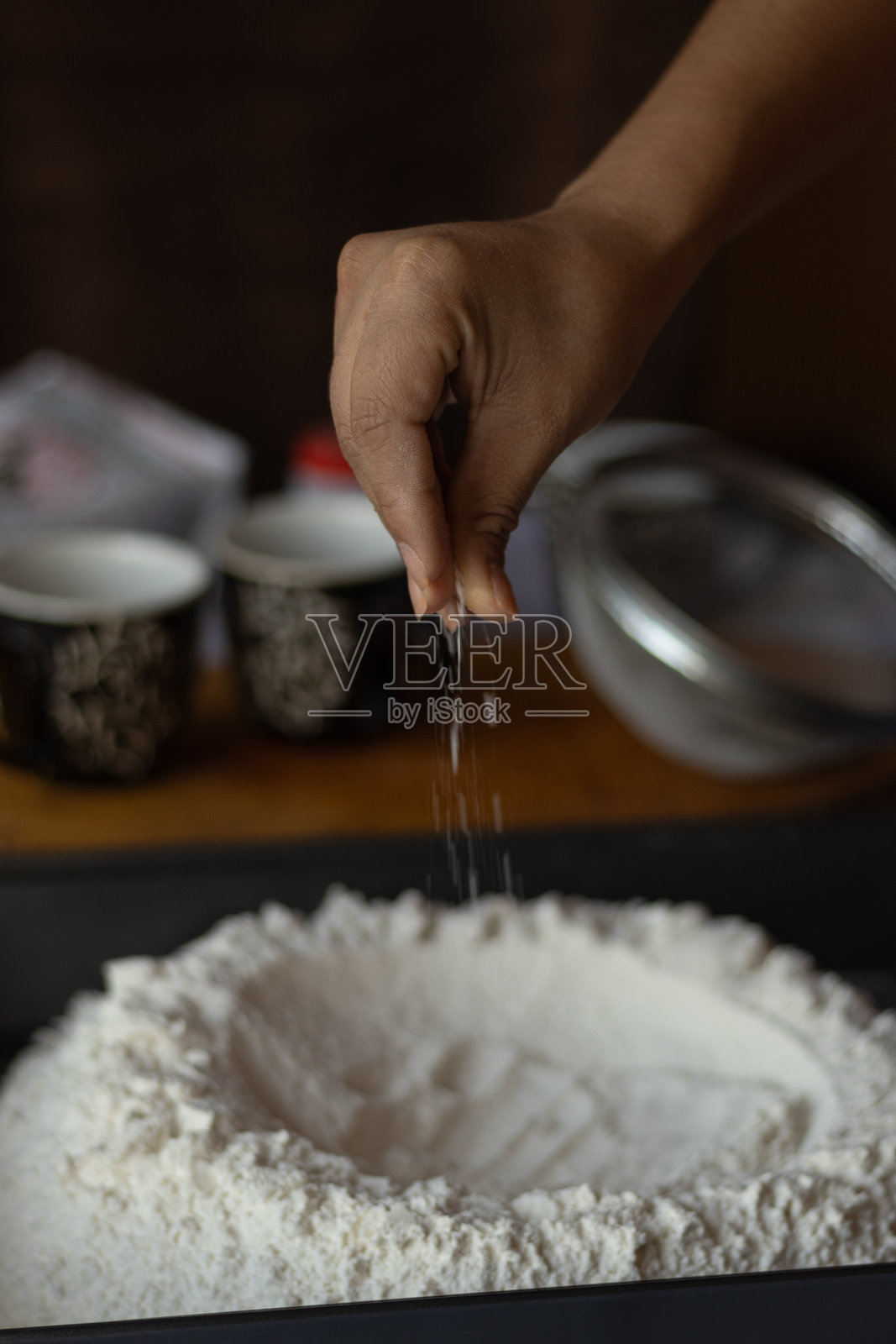 一个无法辨认的人的手在面粉混合物中撒上一撮盐照片摄影图片