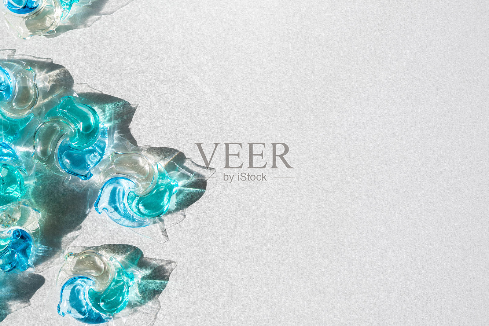 洗衣液胶囊与一堆白色布料背景上的洗衣粉照片摄影图片