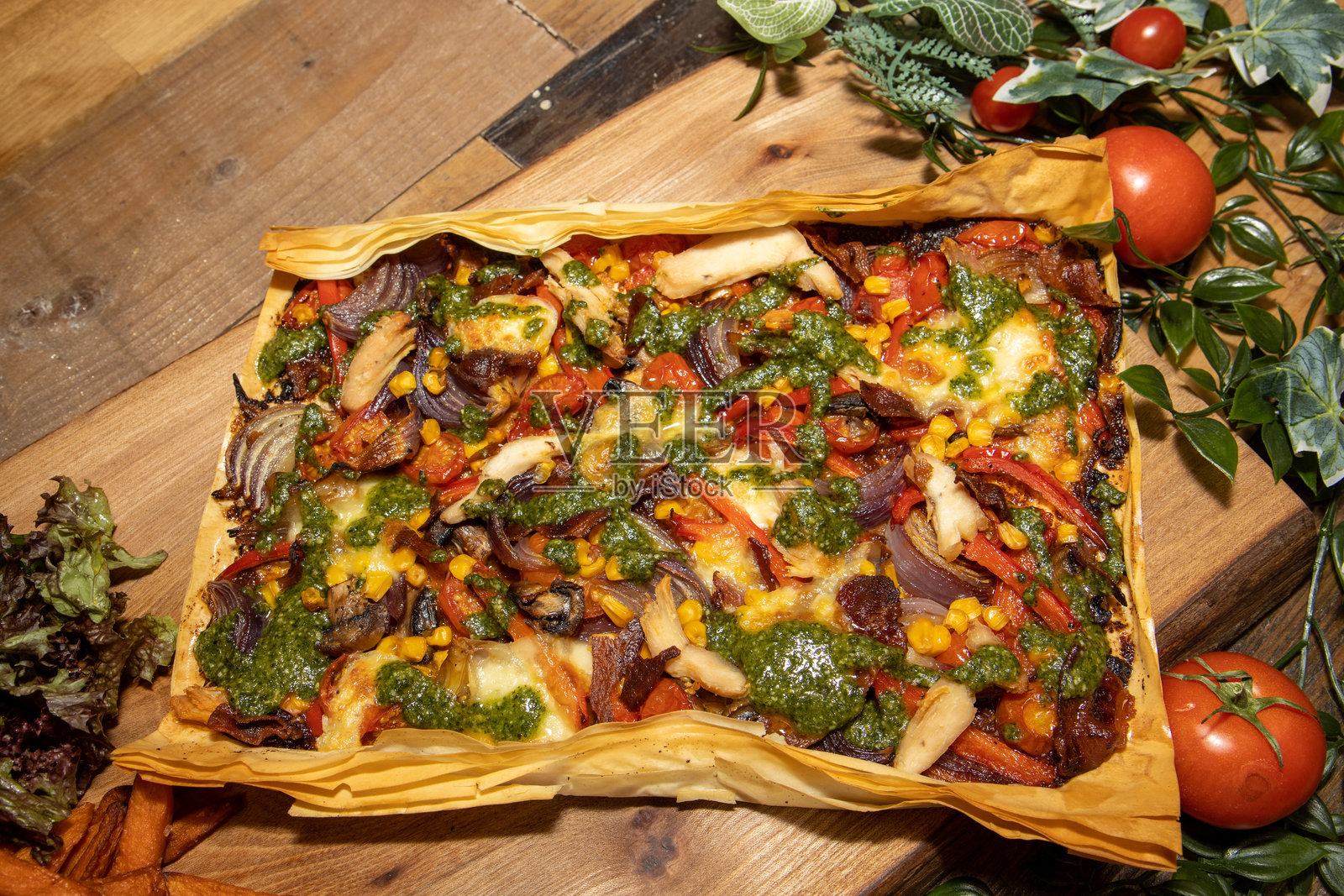 美味的烤蔬菜菲罗饼披萨放在厨房桌子上的木块上照片摄影图片