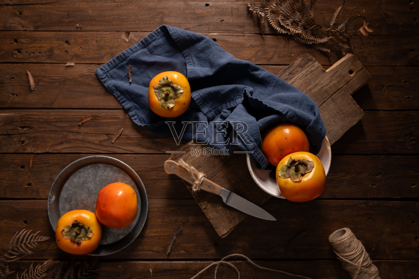 成熟的柿子放在质朴的木桌上照片摄影图片