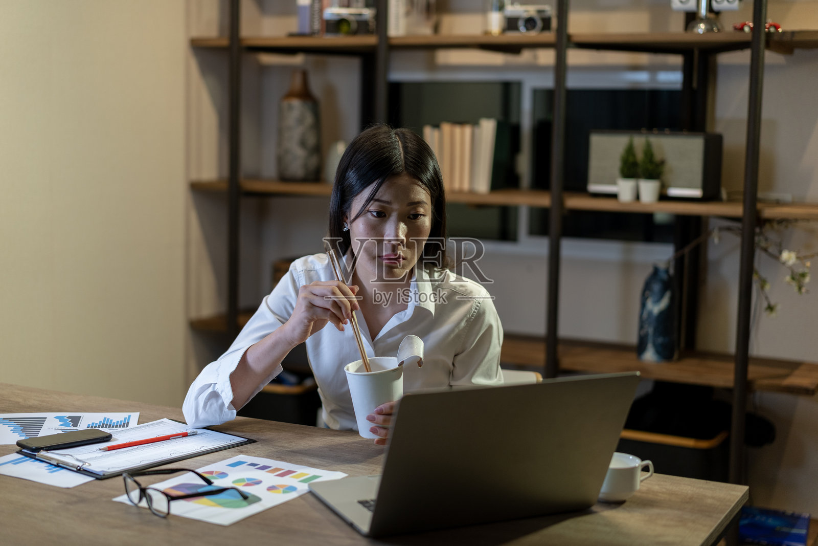 年轻女商人在办公室夜间工作时吃方便面照片摄影图片
