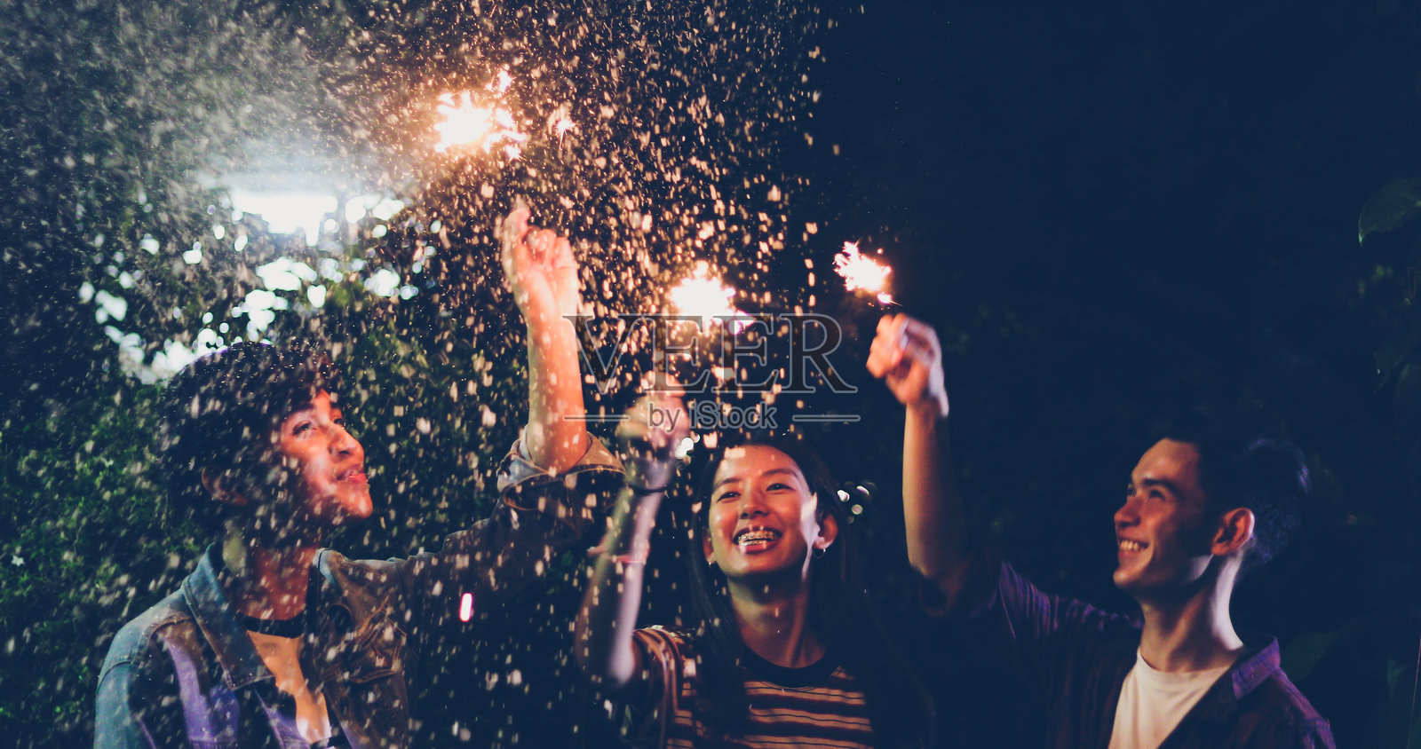 朋友们在夜晚户外手持发光的烟花棒照片摄影图片