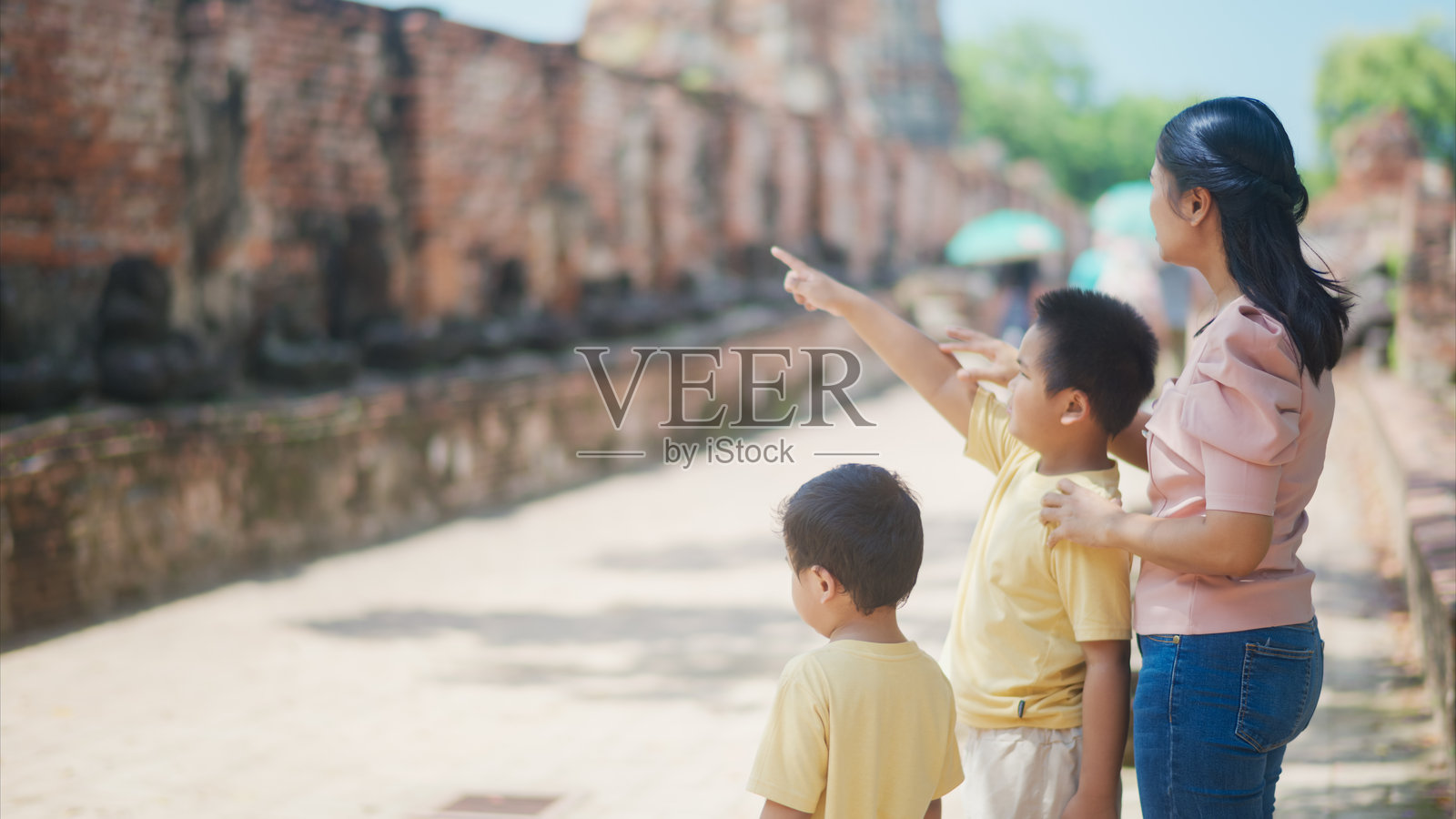一位母亲和她的两个儿子在古城探险,观察历史遗迹,享受在文化遗址的家庭日。照片摄影图片