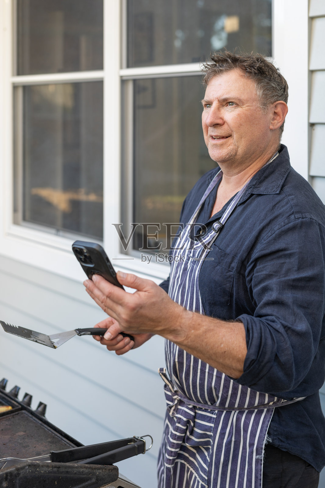 中年男子在烧烤时使用手机照片摄影图片