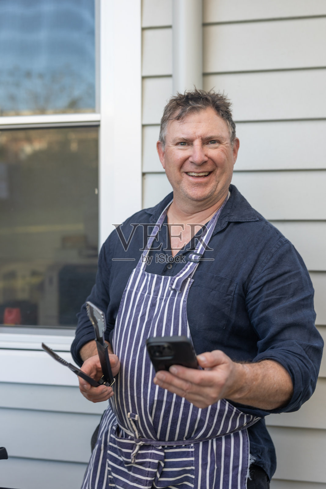 中年男子在烧烤时使用手机照片摄影图片