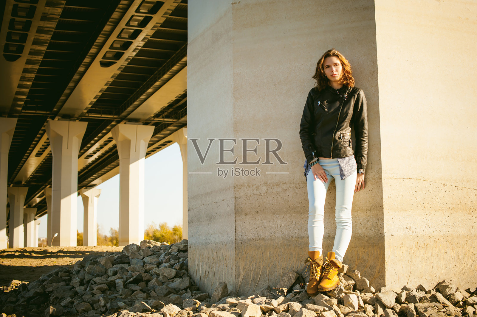 日落时分,年轻女性在桥下站立的肖像照片摄影图片