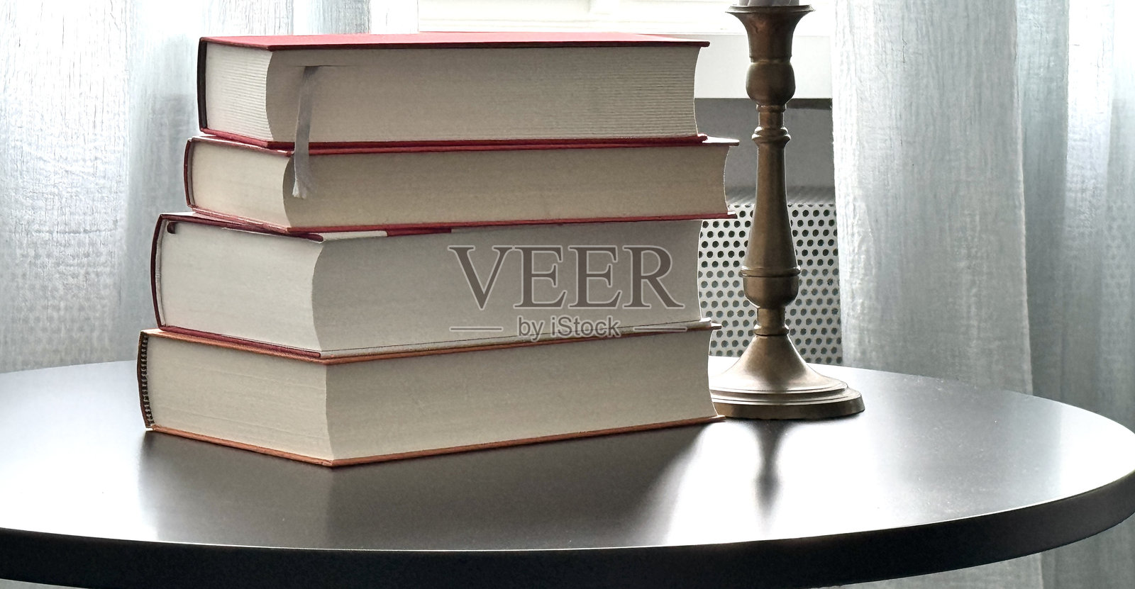 窗边圆桌上的书堆和烛台照片摄影图片