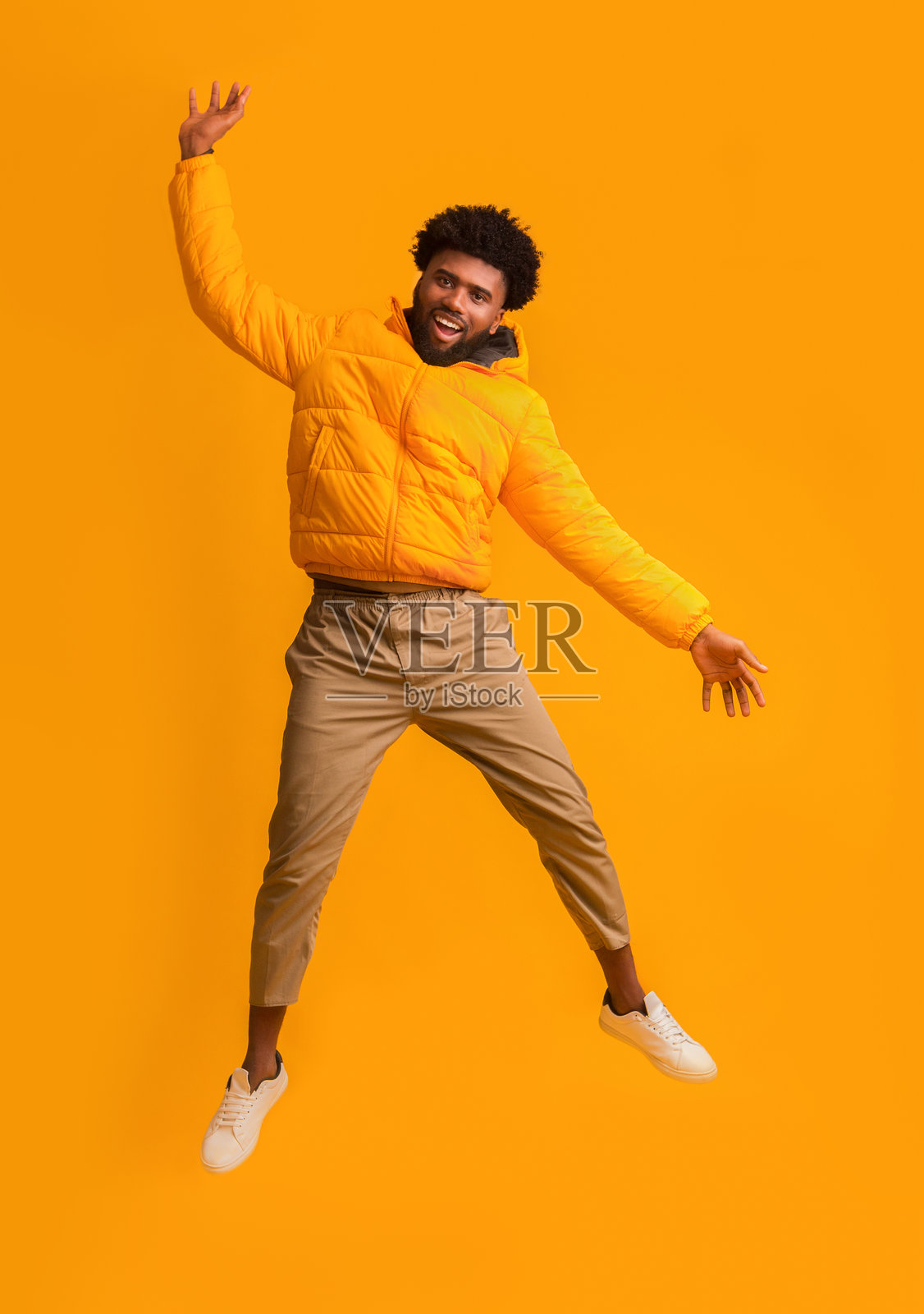 快乐的黑人男子穿着冬季外套高兴地跳起来照片摄影图片