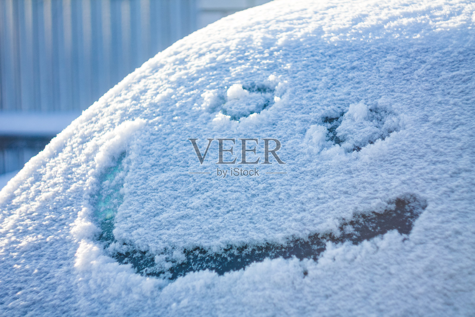 微笑轻柔地描绘在雪面上,营造出一种俏皮的氛围,形成寒冷与温暖情感之间的对比。照片摄影图片