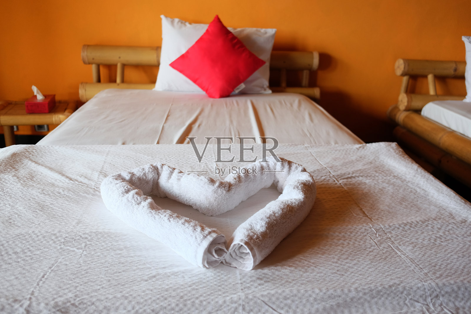 白色心形毛巾放在度假酒店的床上,适合情侣蜜月旅行,情人节假期的目的地旅行。照片摄影图片