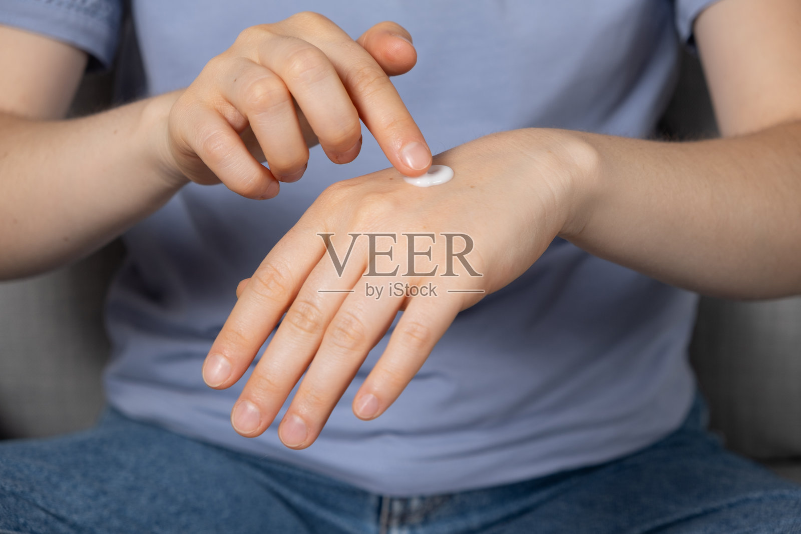 一位女性在手上涂抹护肤霜。护肤与预防。照片摄影图片