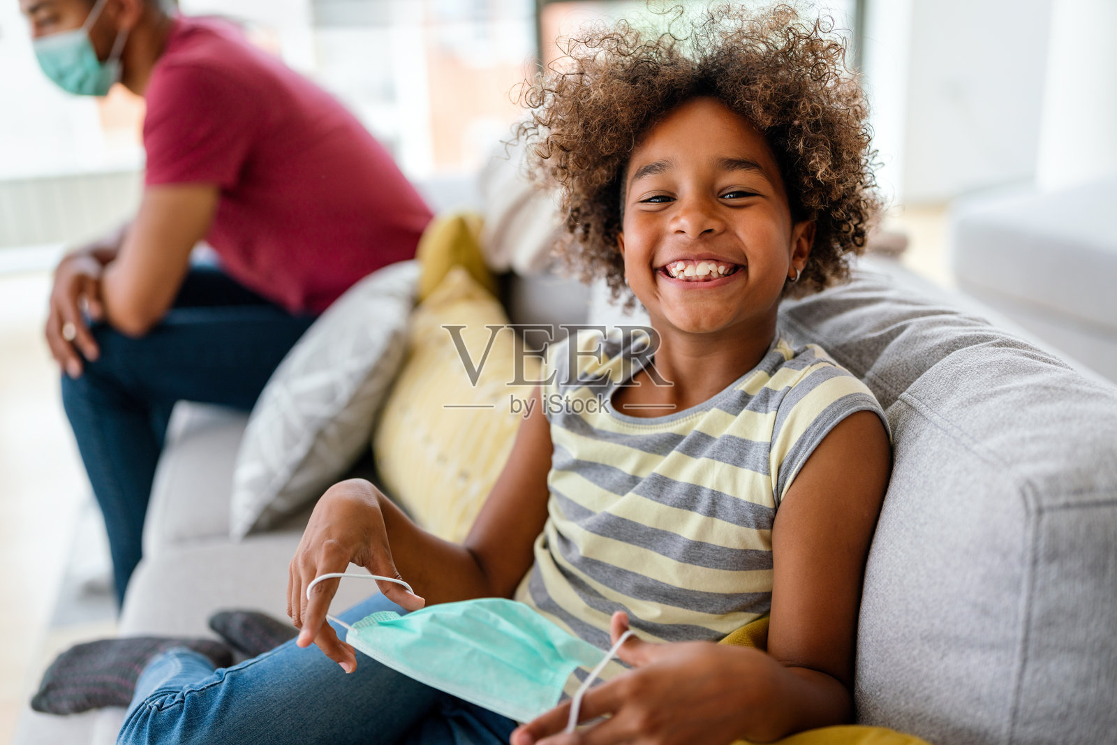 快乐微笑的非裔美国女孩摘下烦人的保护性无菌口罩照片摄影图片