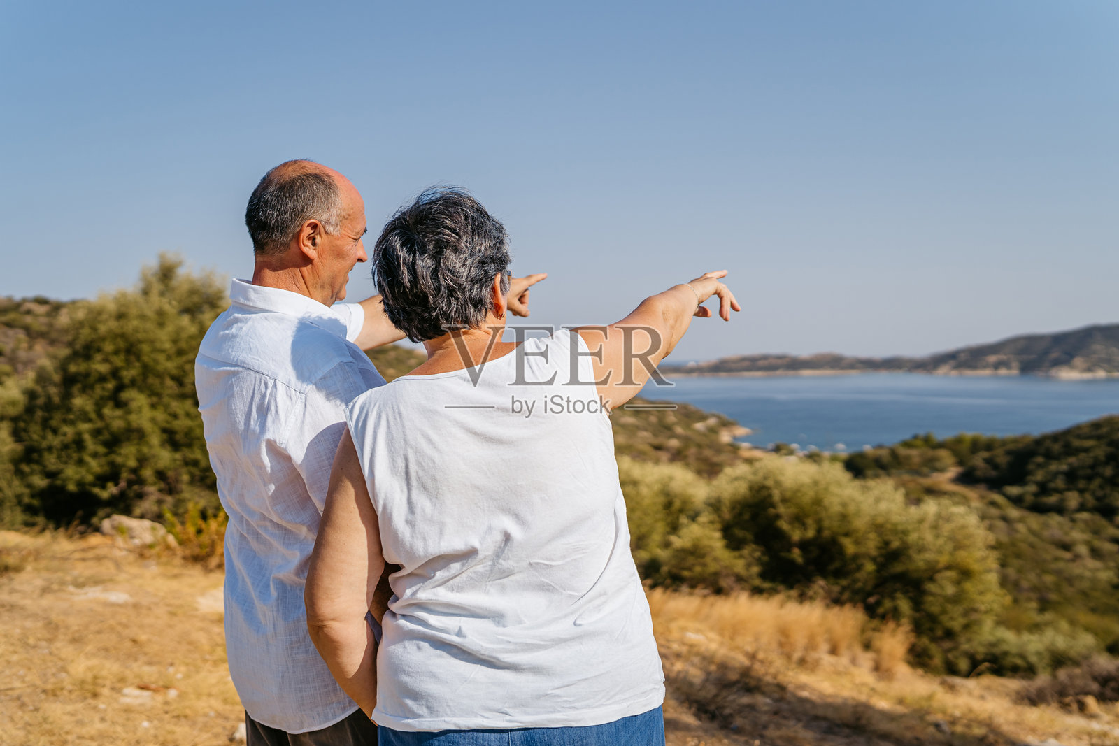 希腊西索尼亚海岸线上的老年夫妇欣赏海边风景照片摄影图片