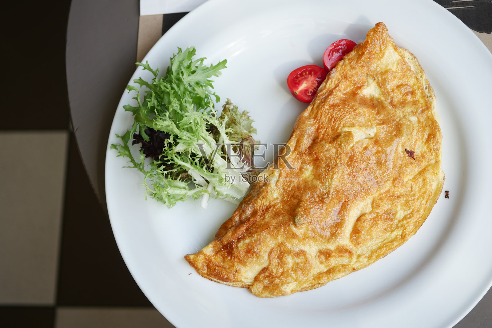 简单的鸡蛋煎蛋卷,配有樱桃番茄和香草,摆放在桌子上照片摄影图片