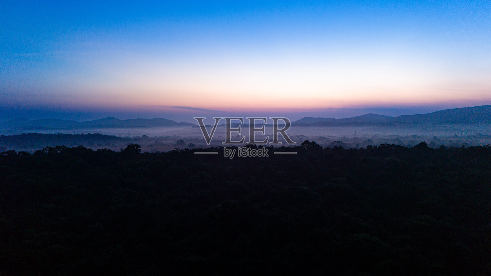 Sunrise over misty hills in Sri Lankas landscape. The sun rises slowly, casting a soft glow over mist-covered hills and valleys in the serene landscape of Sri Lanka.照片摄影图片