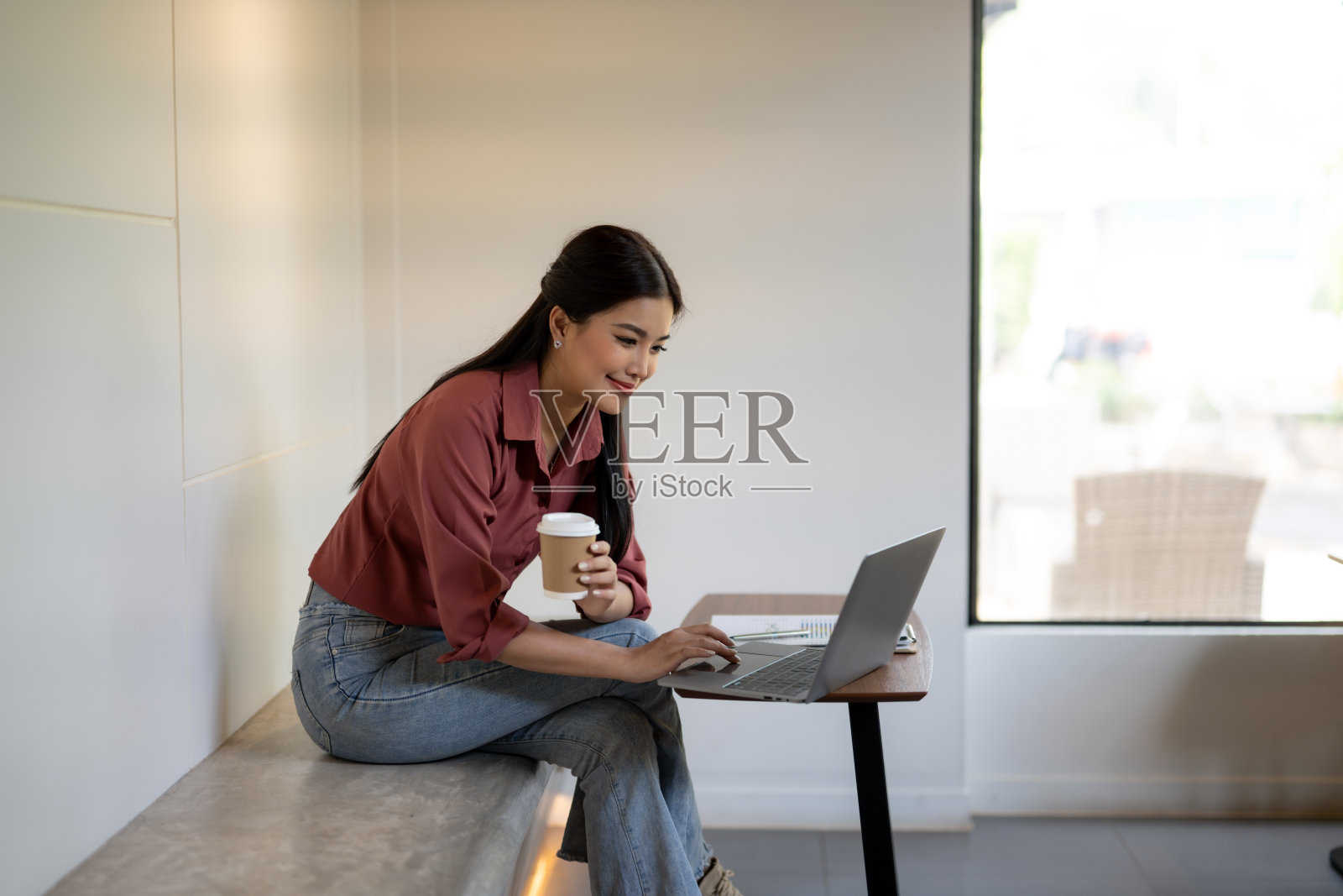 一位自信的女商人在咖啡馆里一边喝咖啡,一边使用笔记本电脑工作。照片摄影图片