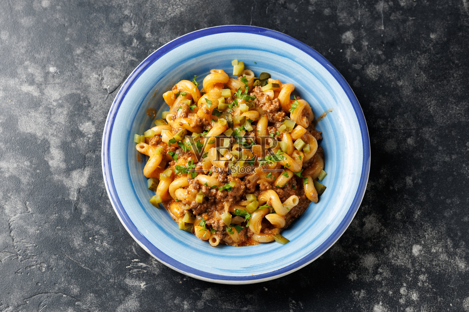 芝士汉堡意大利面,配有碎牛肉、融化的奶酪和腌黄瓜照片摄影图片