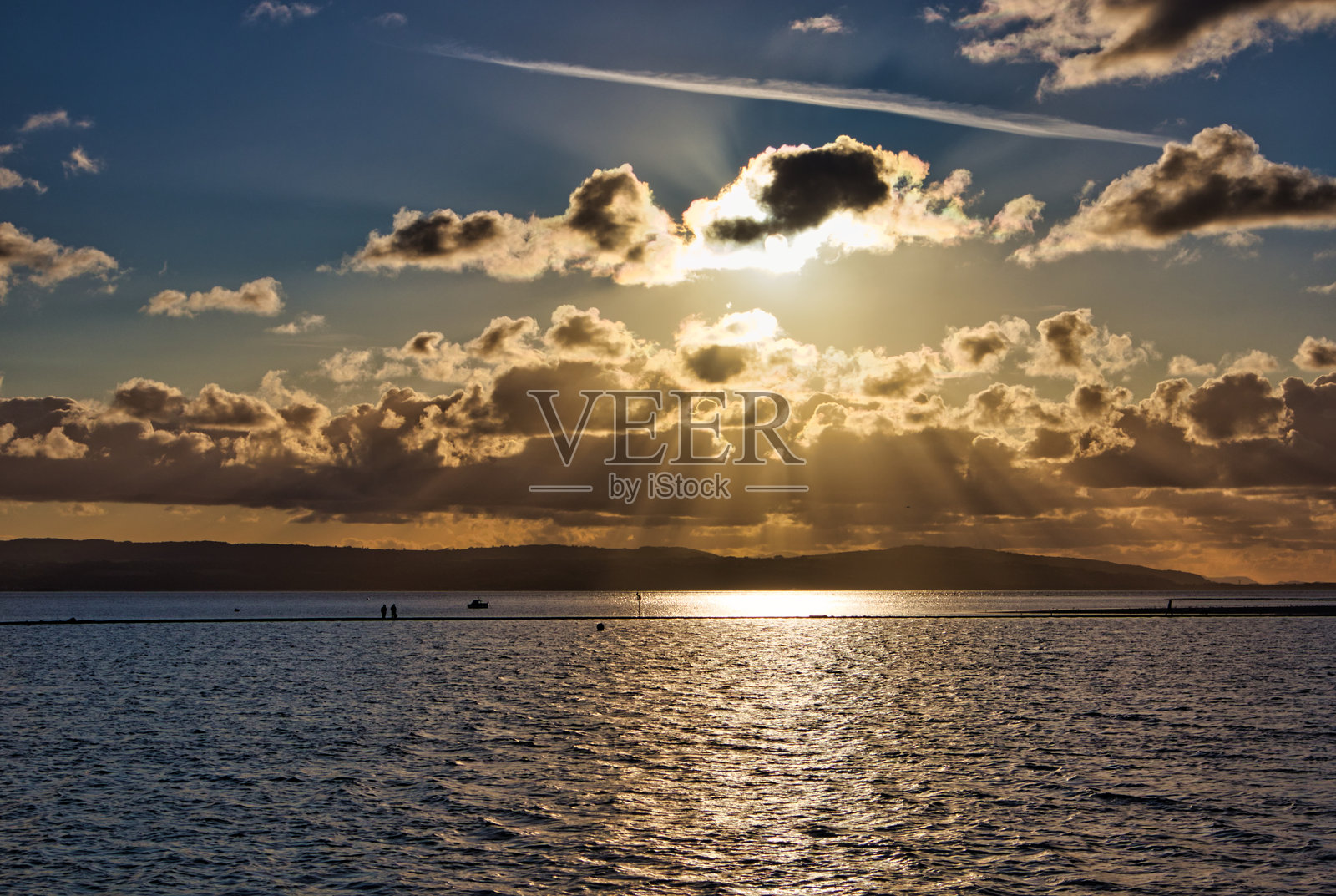 人们在距离较远的地方悠闲地散步,地点是英格兰梅西塞德郡的西柯比海洋湖。照片摄影图片