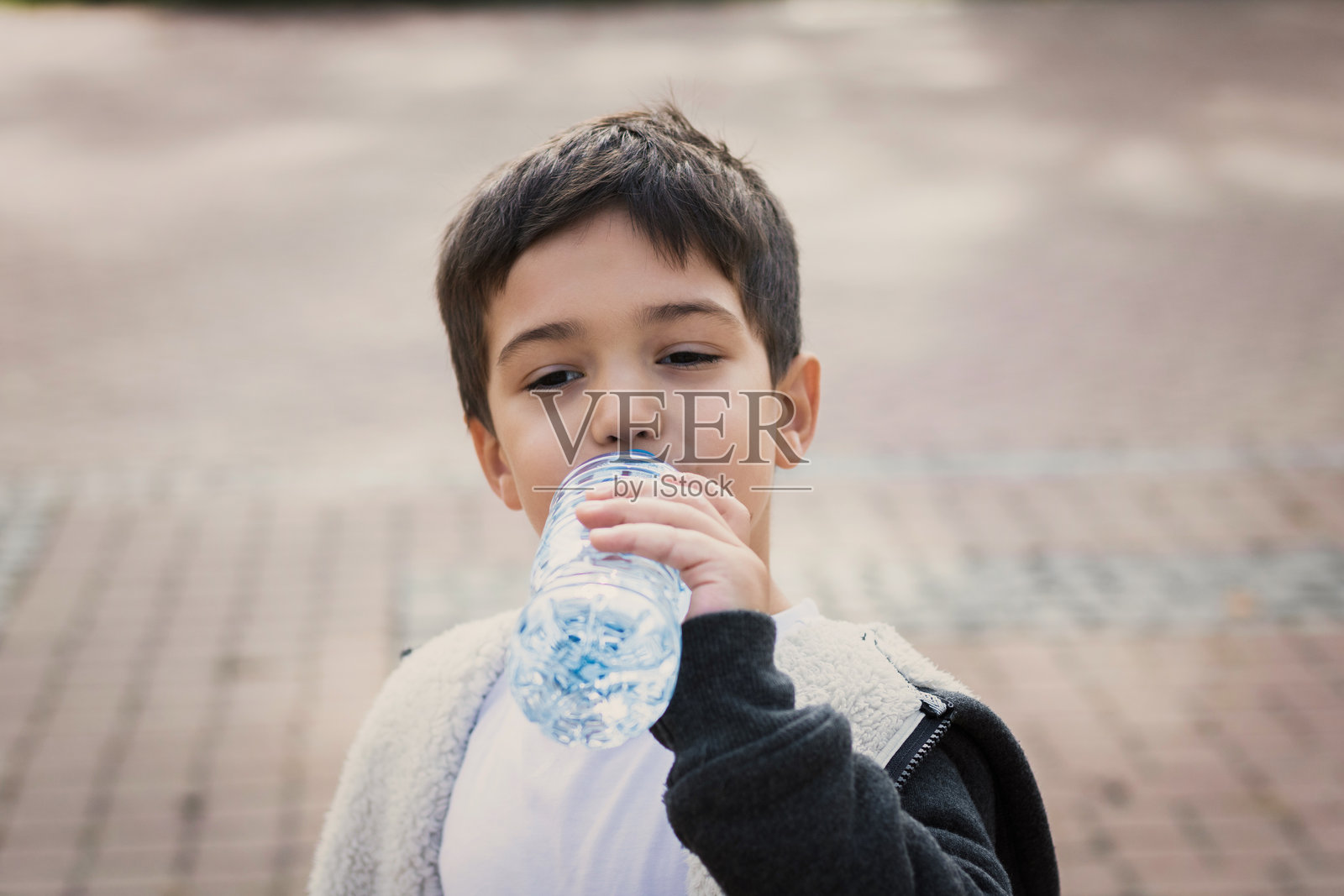 男孩在步道上喝水瓶里的水照片摄影图片