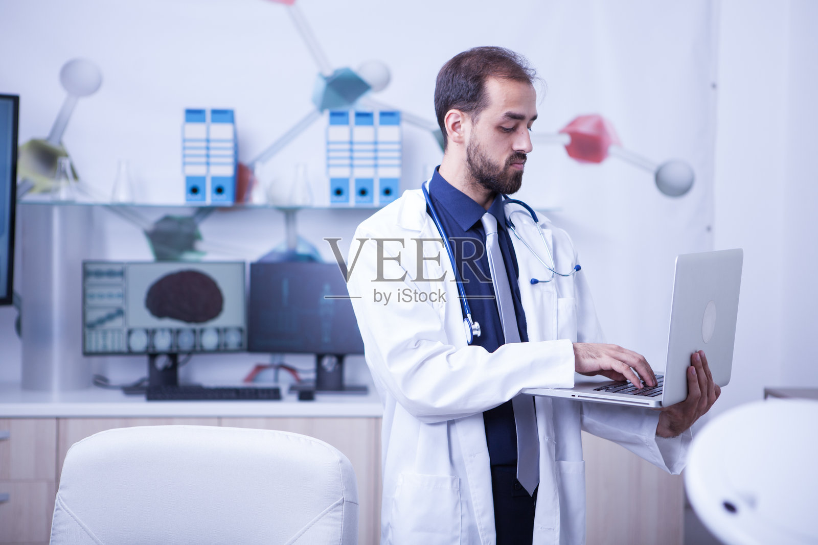 年轻医生在办公室站着,使用笔记本电脑工作照片摄影图片