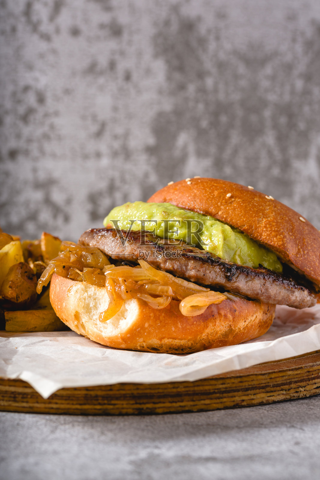 木制砧板上的汉堡,配有焦糖洋葱和鳄梨照片摄影图片