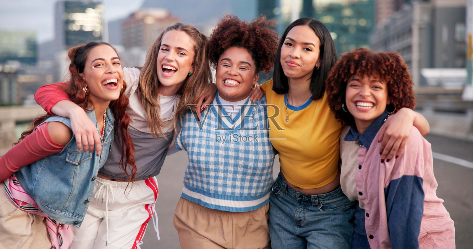 朋友们在城市中拥抱,展现出酷炫的风格、时尚潮流和休闲装扮。在街头放松,城市中的人们欢笑、微笑,享受周末、假期或节日的快乐。照片摄影图片