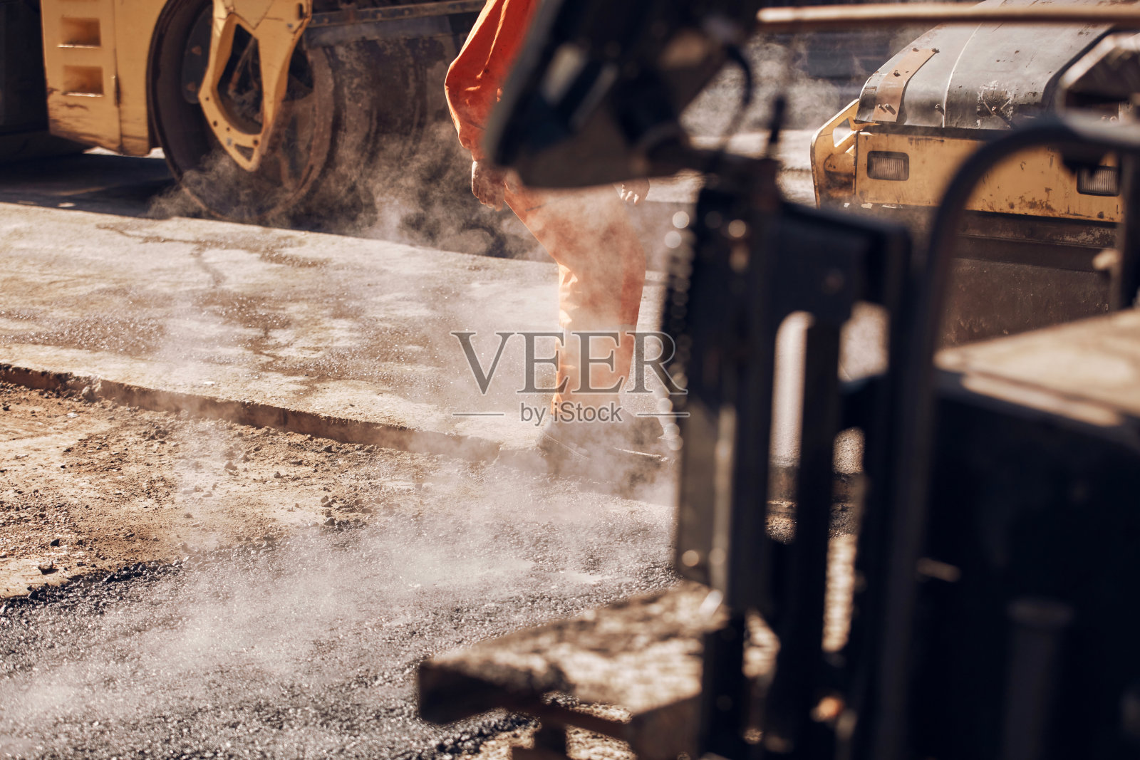 建筑工人在公共街道上铺设新的沥青层。照片摄影图片