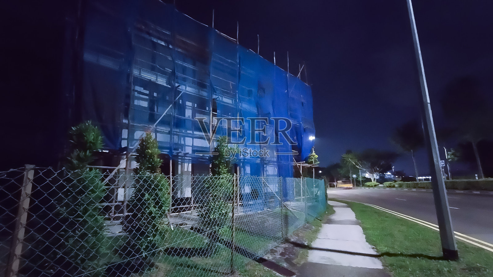 夜晚黑暗中覆盖蓝色网状物的木质脚手架照片摄影图片