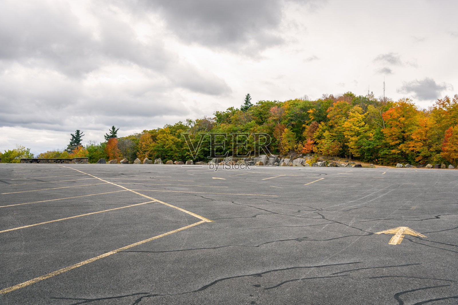 山顶的荒废停车场,阴云密布的秋日。背景中有秋天的树木。照片摄影图片