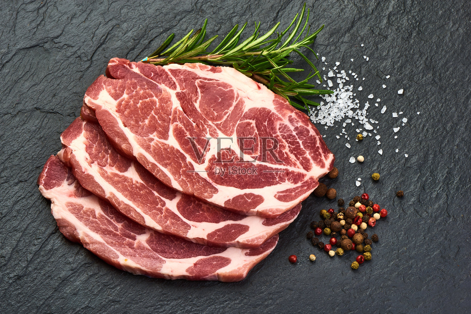 香草调味的猪里脊肉片,摆放在石板上。照片摄影图片