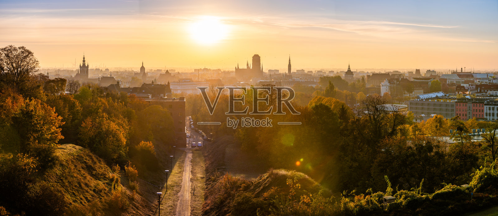 格但斯克天际线和城市景观在明亮的日出中被照亮,长长的道路穿过树木。照片摄影图片