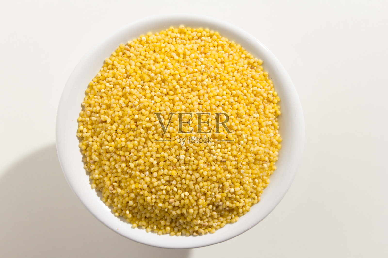 白色背景下碗中盛放的黄色的种子俯视图照片摄影图片