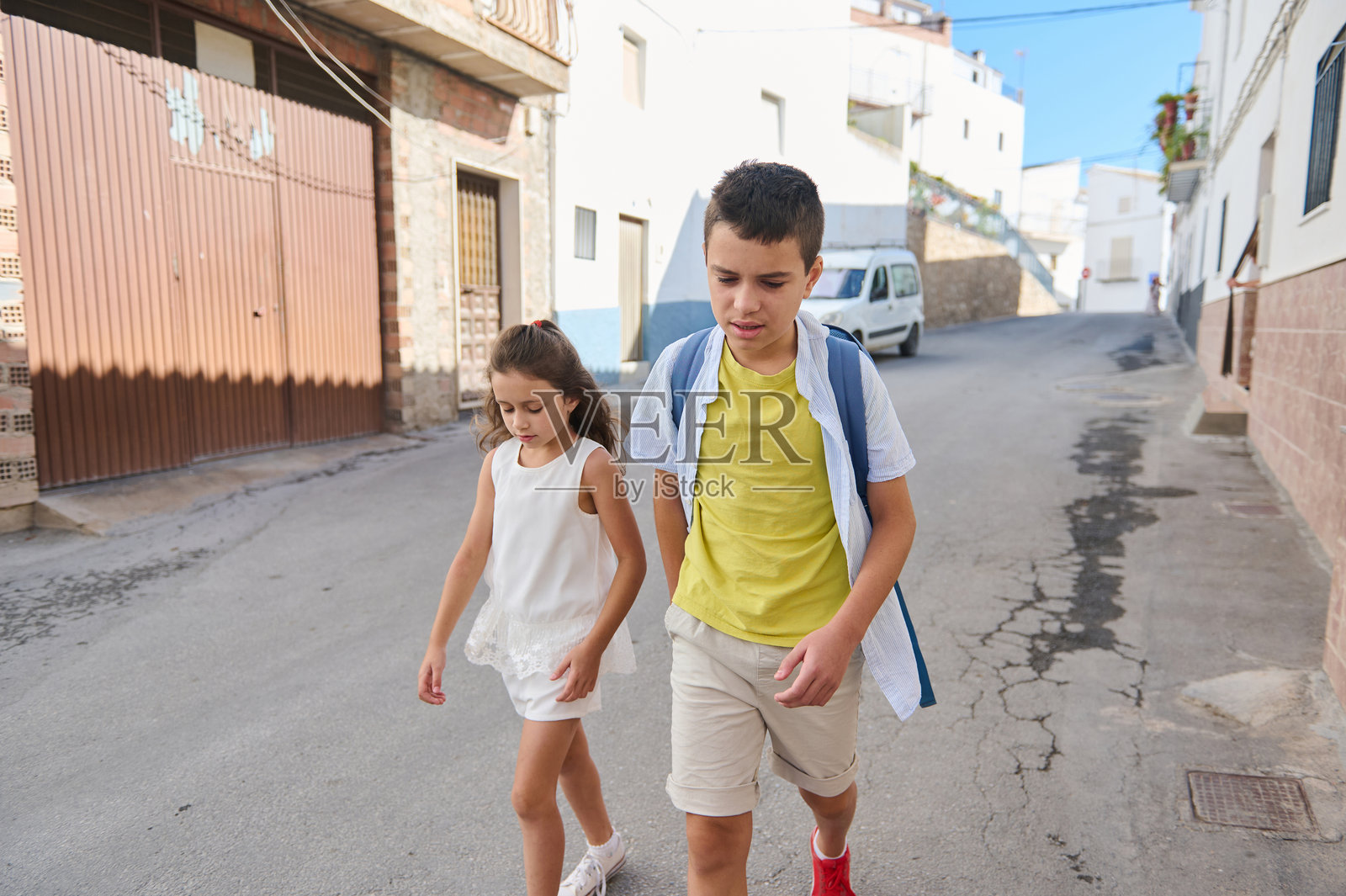 孩子们在阳光明媚的城市街道上一起走着照片摄影图片