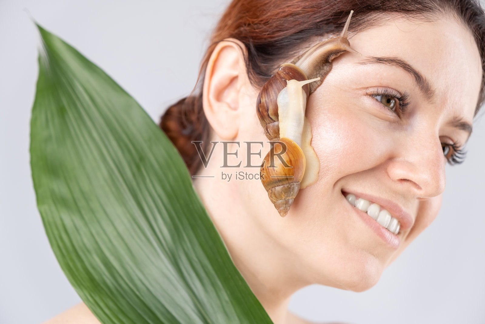 微笑的年轻女性脸上有一只蜗牛的特写镜头照片摄影图片