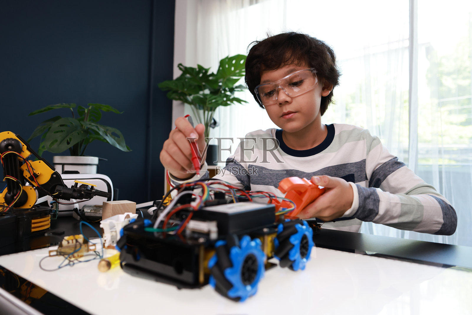 一个年轻的小学生专注于组装和编程机器人汽车。看到这个年龄的孩子能够构建和操作机器人,令人印象深刻。照片摄影图片