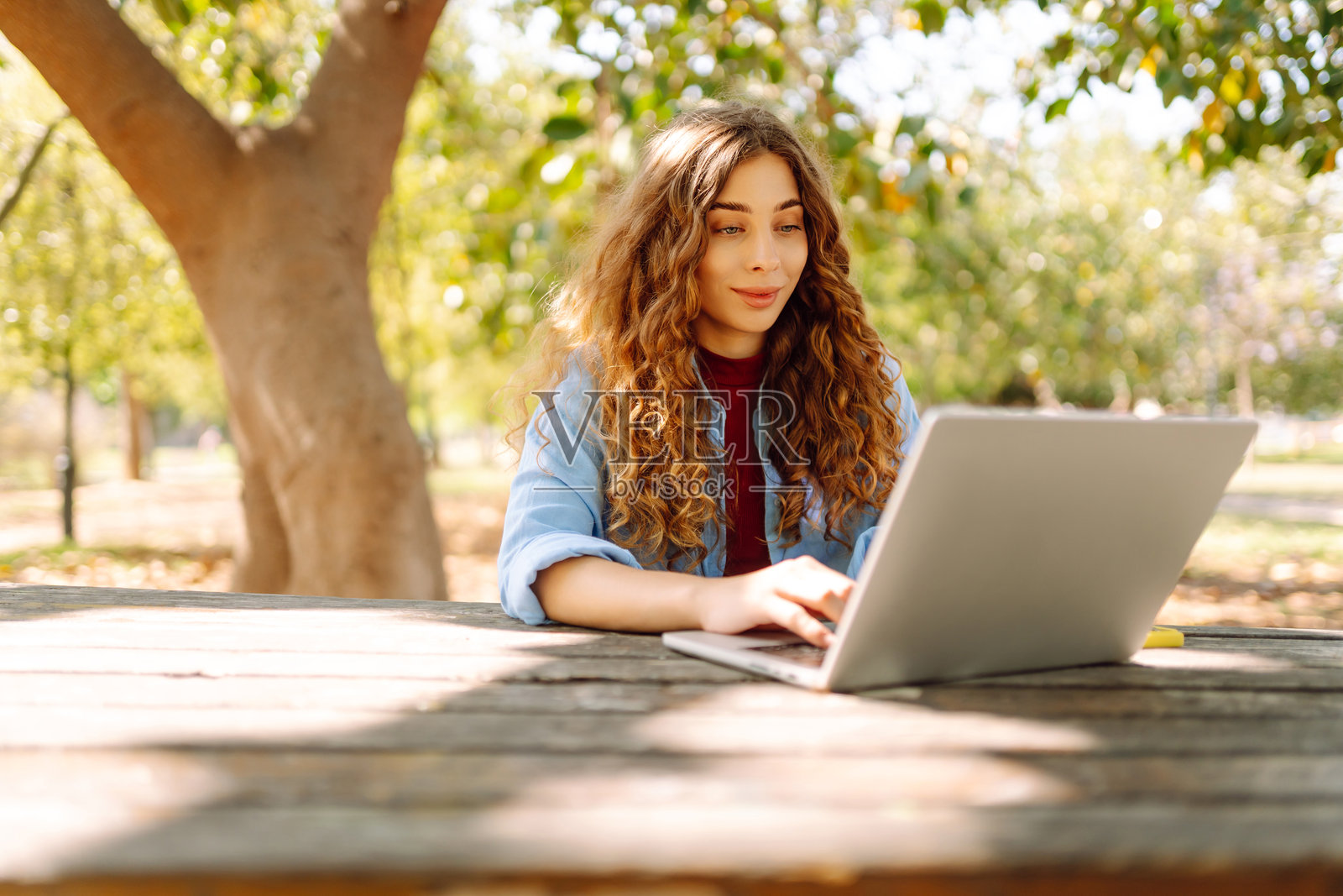 年轻女性带着笔记本电脑来到公园,享受新鲜空气并工作。照片摄影图片