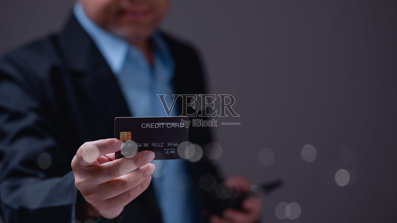 精致的个人手持信用卡,象征着财务赋权、便利性和数字交易时代,模糊的背景增强了对卡片的关注。照片摄影图片