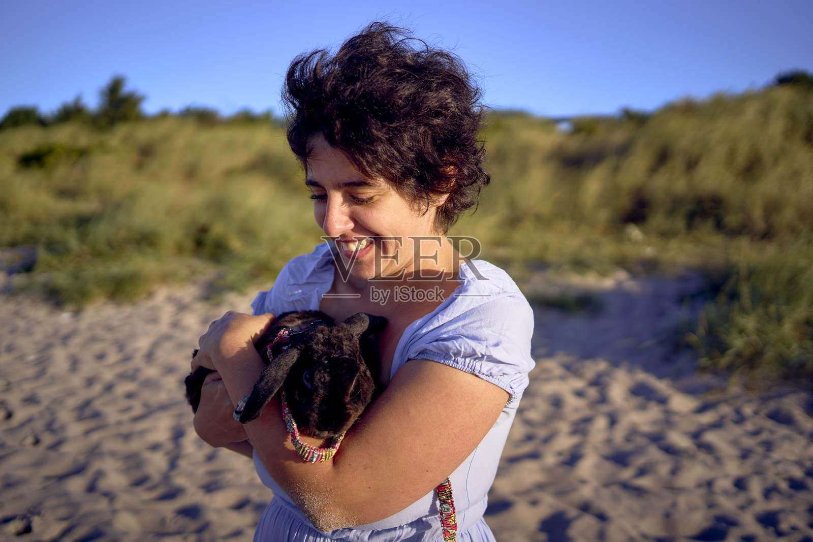 年轻的丰满女性在哥本哈根海边与她的宠物兔子散步和玩耍照片摄影图片