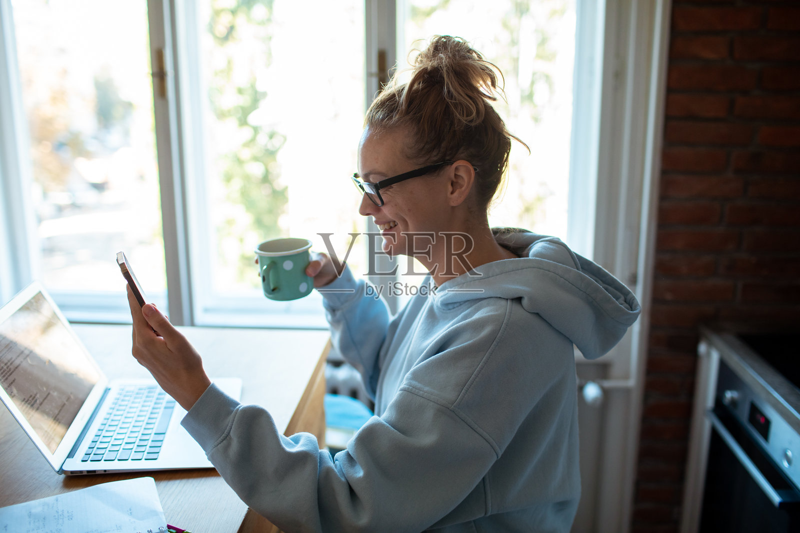 年轻女性在家中使用手机,同时学习或工作在笔记本电脑上照片摄影图片