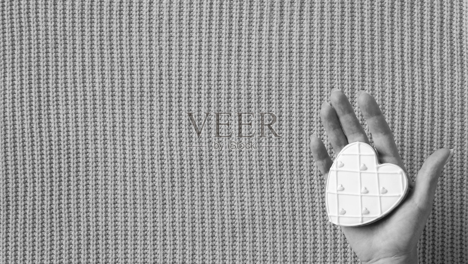 黑白纹理背景上手持的心形白巧克力照片摄影图片