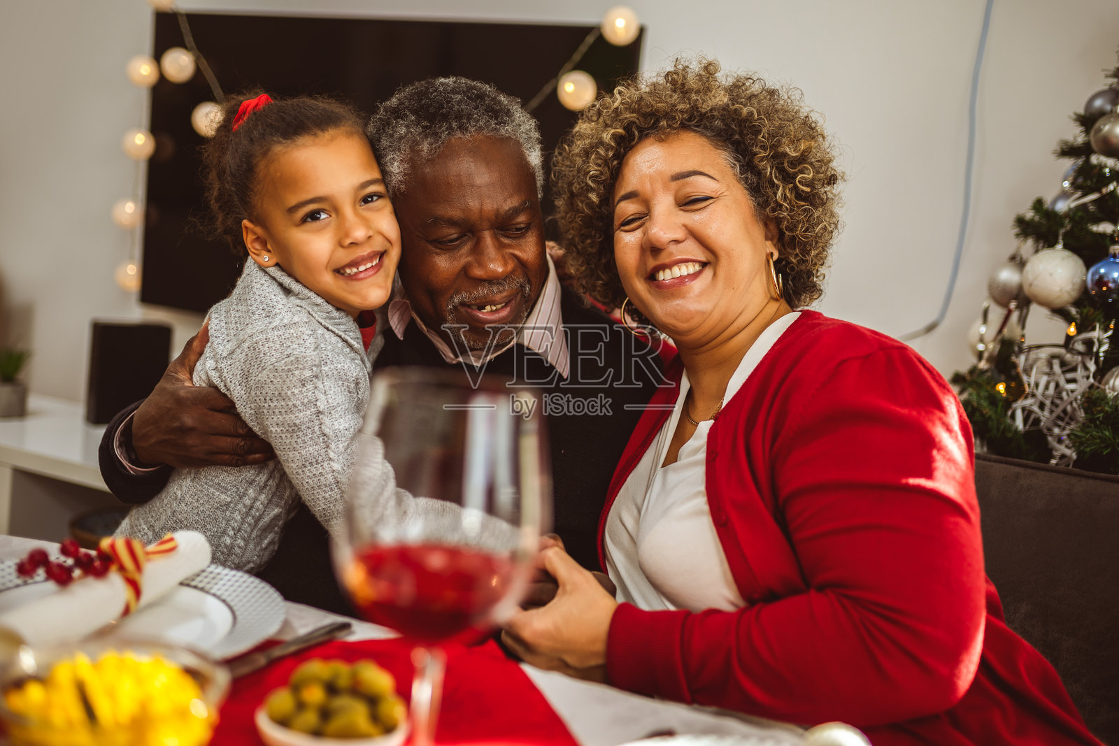 非裔美国人孙女在感恩节晚餐时与祖父母拥抱。照片摄影图片
