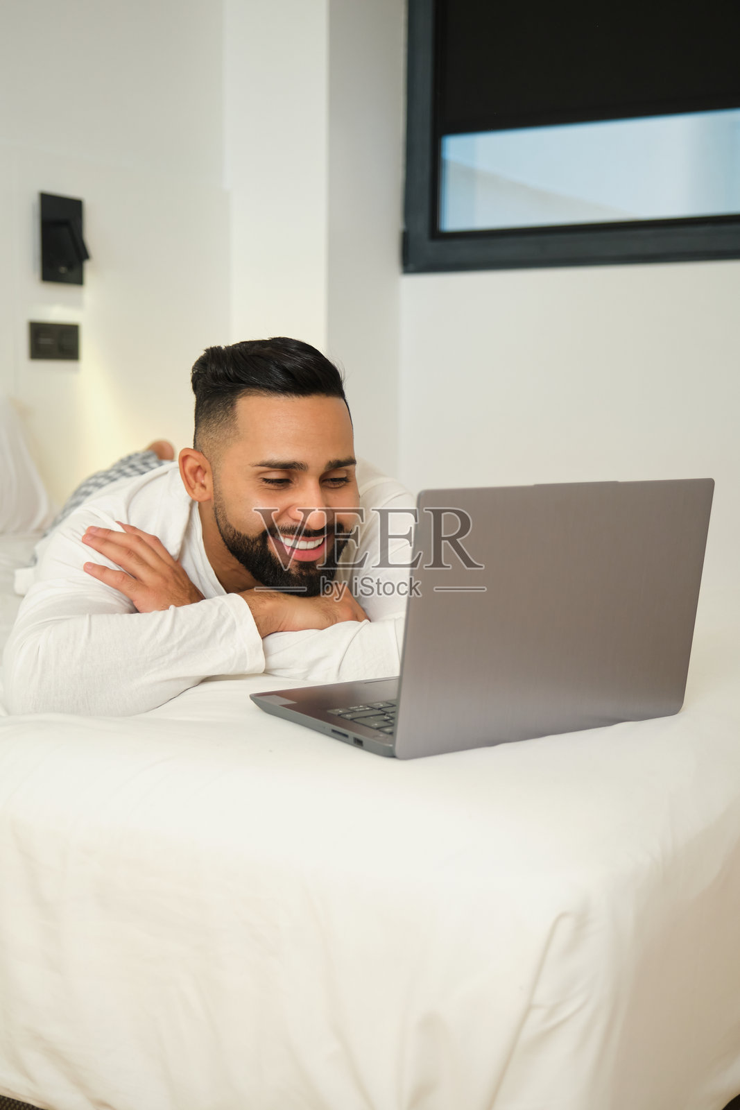 快乐的男人躺在床上使用笔记本电脑照片摄影图片