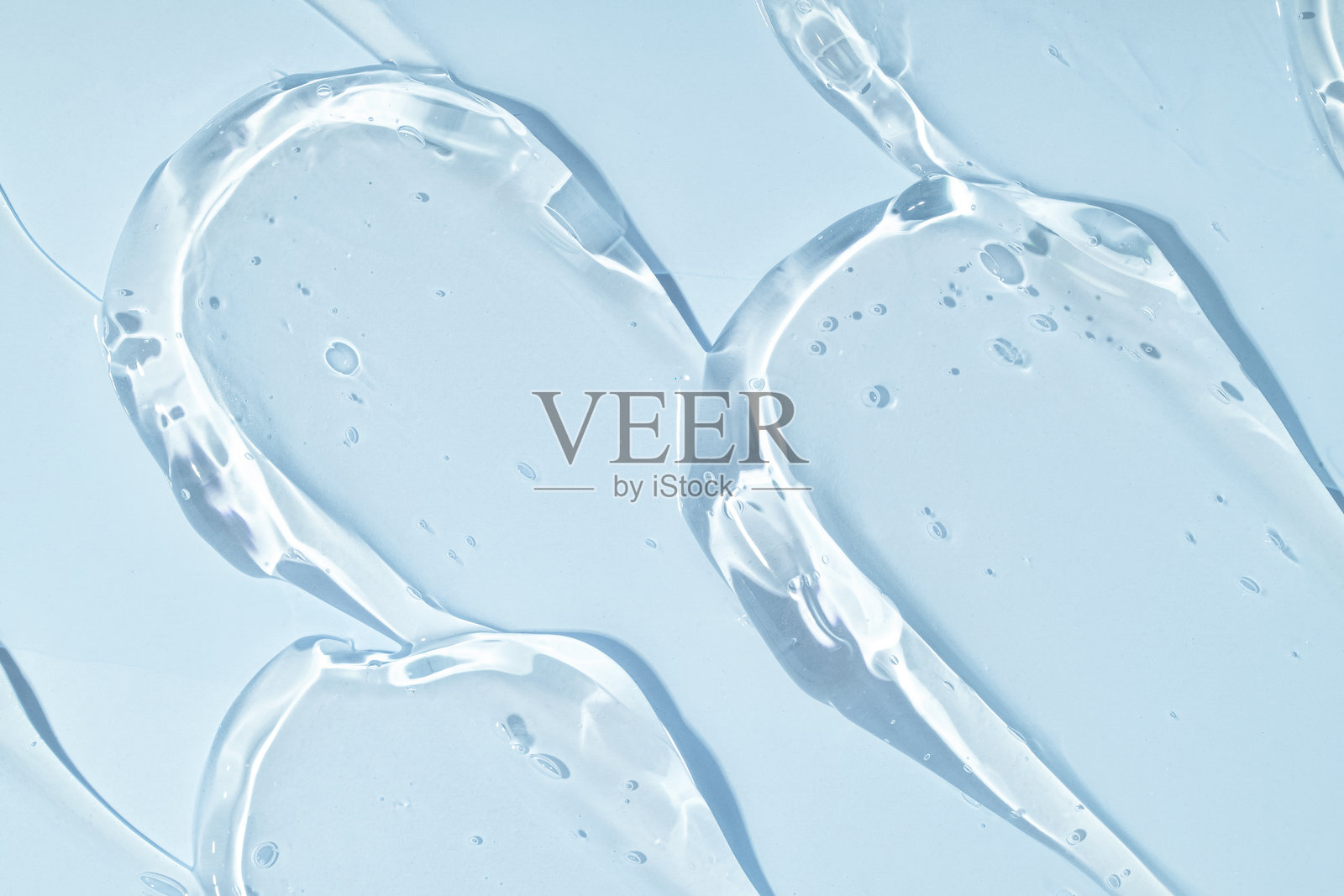 自然透明的凝胶质地涂抹、污迹、色块在蓝色背景上照片摄影图片