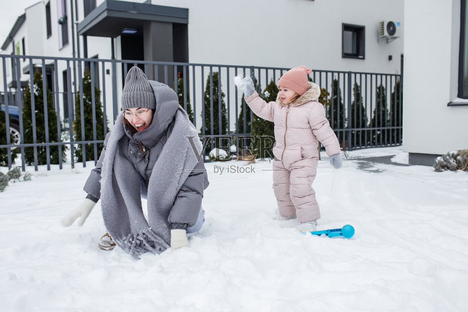 快乐的母女在冬日的郊区社区里玩新鲜的雪照片摄影图片
